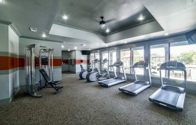 a gym with cardio equipment and windows