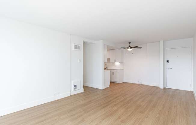 an empty living room and kitchen with white walls and wood flooring at Avenue Two Apartments, Redwood City