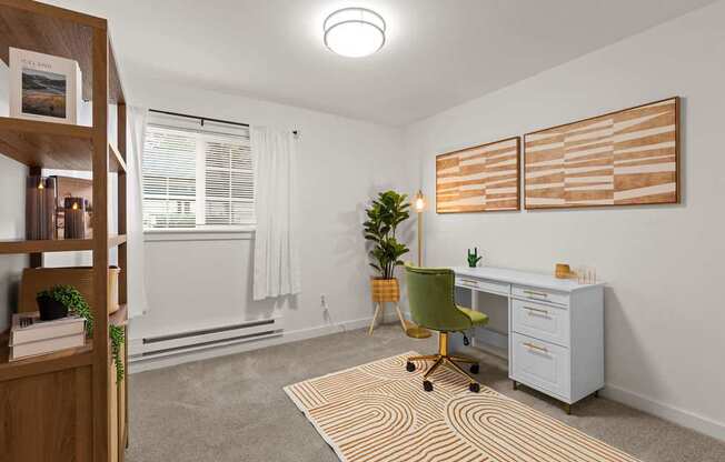 A room with a desk, chair, and two artworks on the wall.