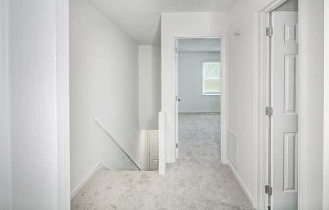 an empty room in a house with white walls and a carpeted staircase