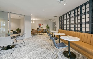 a lounge area with tables and chairs and a large window
