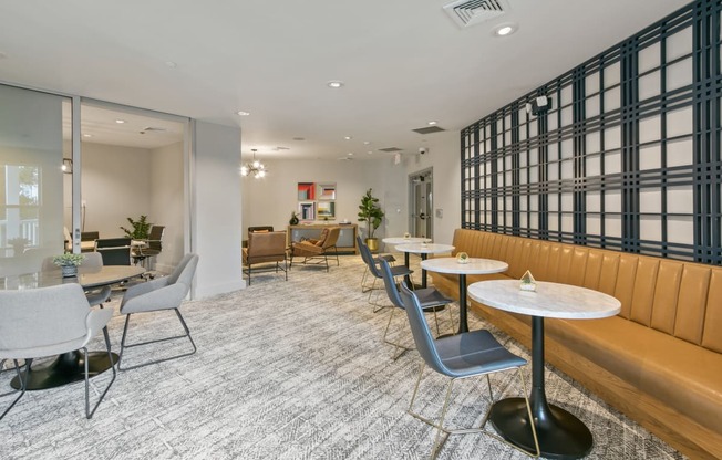 a lounge area with tables and chairs and a large window