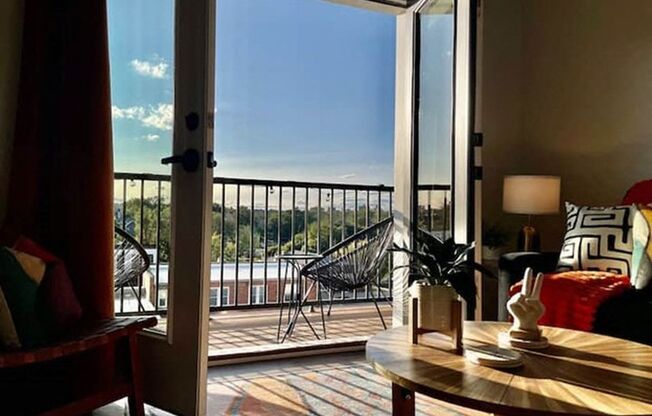 A balcony with a table and chairs overlooking a railing.