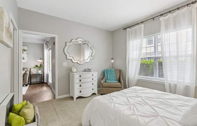 A bedroom with a white bed and a mirror on the wall.