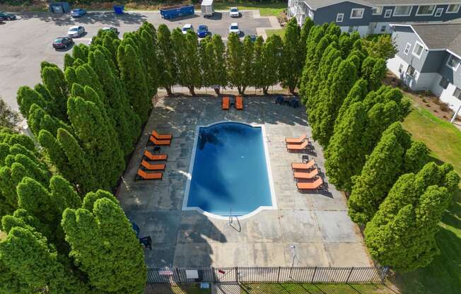 an aerial view of a swimming pool surrounded by trees at Town & Country Apartments - Wixom, MI, Wixom, 48393