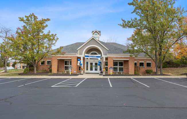 the front of a brick building with a parking lot