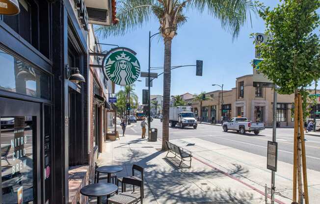 a city street with a starbucks sign on the side of a tree