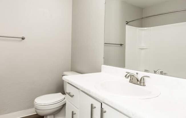 A white bathroom with a toilet, sink, and mirror.