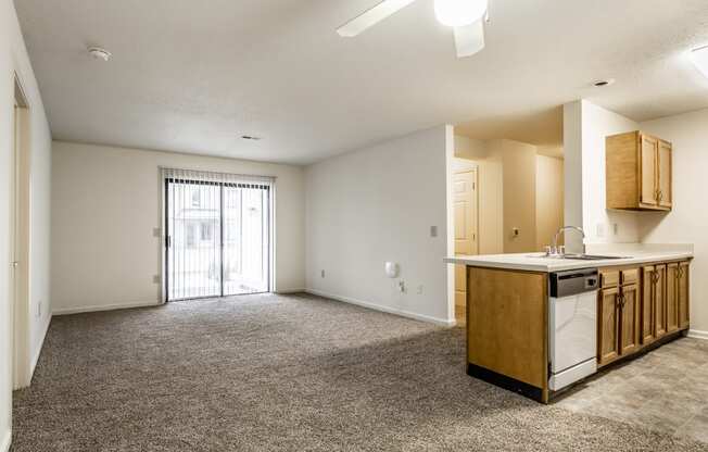 an empty living room with a kitchen and a door to a balcony at Pheasant Run in Lafayette, IN 47909