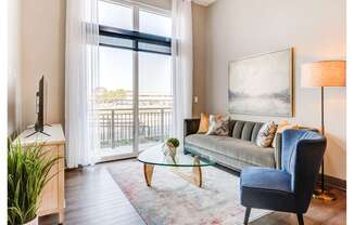 A living room with a blue chair and a glass table.