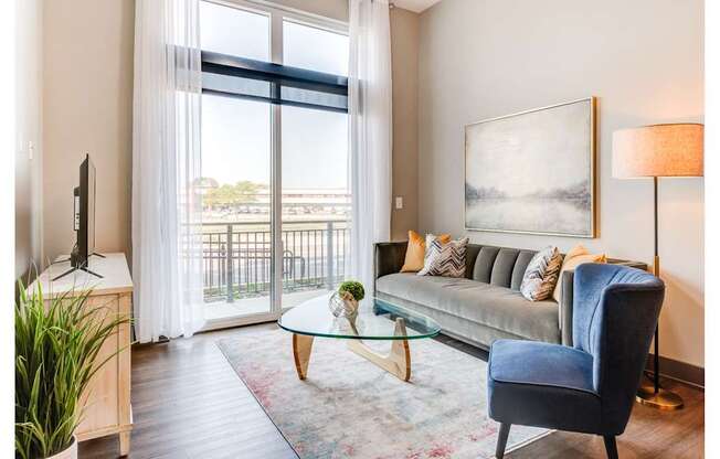 A living room with a blue chair and a glass table.
