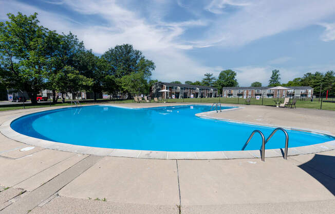 a swimming pool with trees and apartments in the background