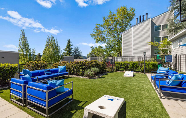 a patio with blue lounge chairs and a table on the grass