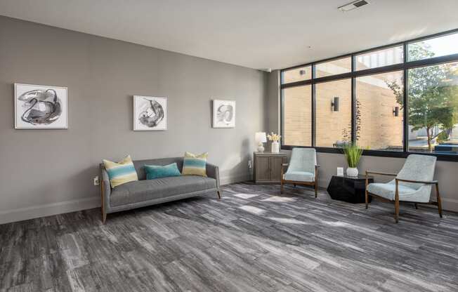 a living room with a couch and two chairs and a window