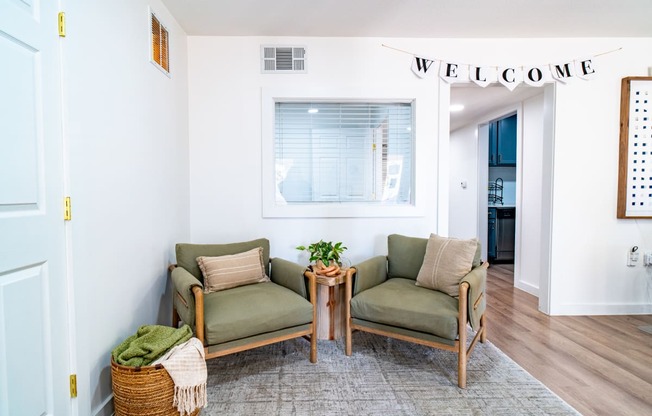 a living room with two chairs and a welcome sign on the wall