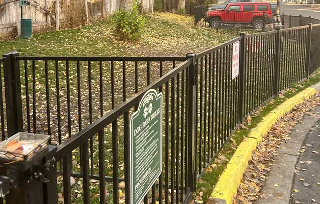 Fenced in dog park with a sign that lists dog park rules