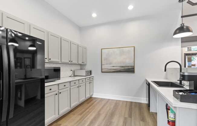 a kitchen with white cabinets and black appliances and a black refrigerator