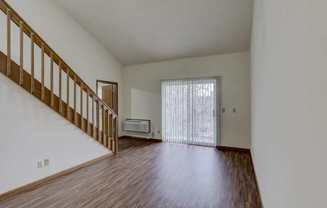 the living room and entryway of an empty house with wood flooring and a