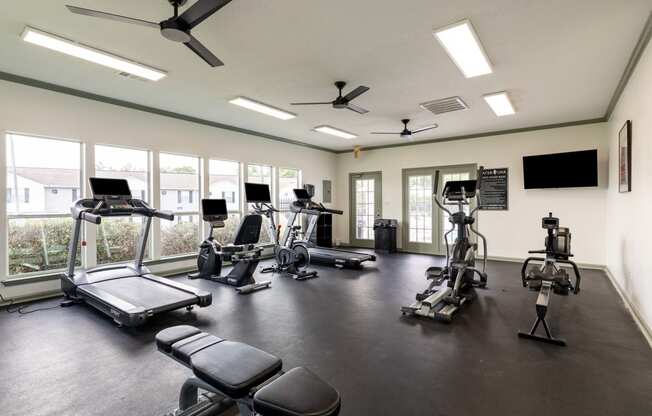 a gym with cardio equipment and windows in a building