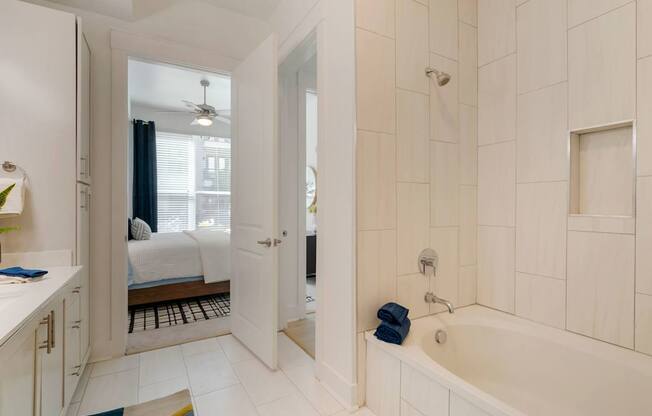A white bathroom with a tub, sink, and mirror.