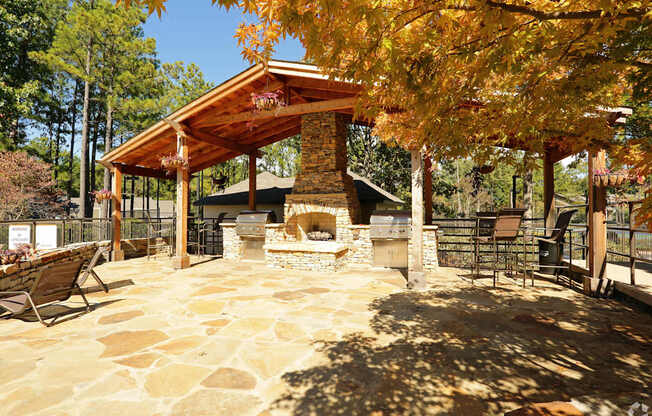 A patio with a fireplace and a table surrounded by trees.