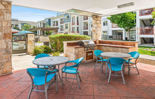 a patio with a table and chairs and a grill