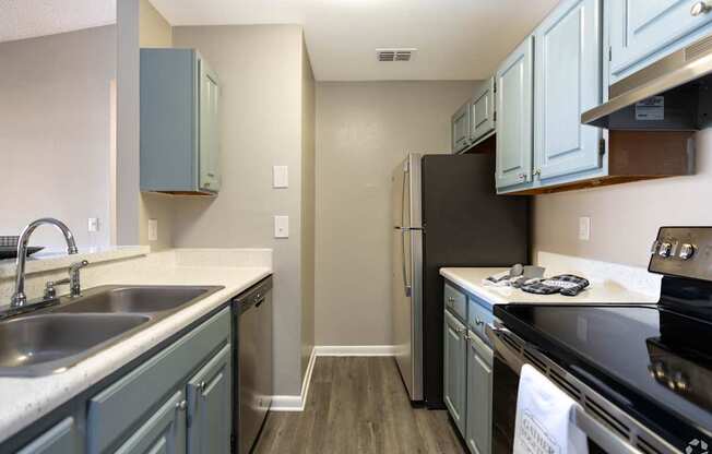 a kitchen with stainless steel appliances and blue cabinets at Aqua Bay Apartments in Naples, FL 34116