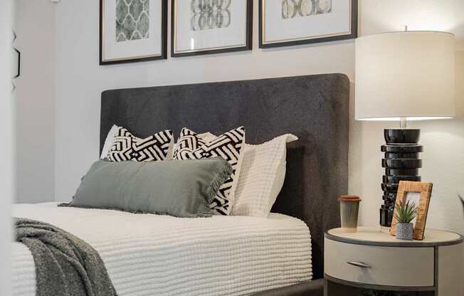 A bed with a grey headboard and a grey pillow is in the image.