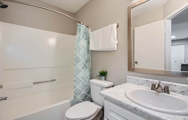 A bathroom with a toilet, sink, and shower.