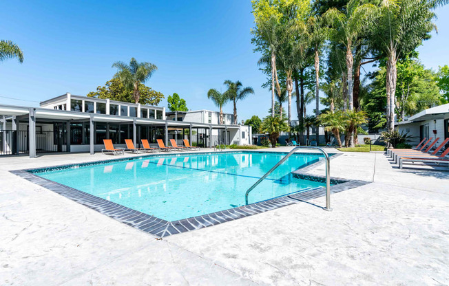 A swimming pool with a metal ladder and orange chairs.