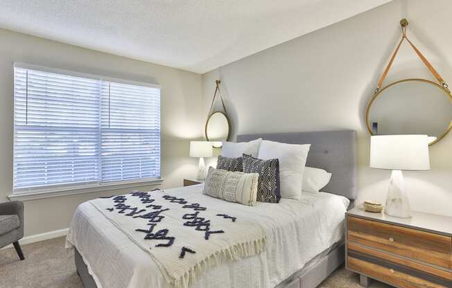 a bedroom with a large window and a large bed with a white comforter and pill