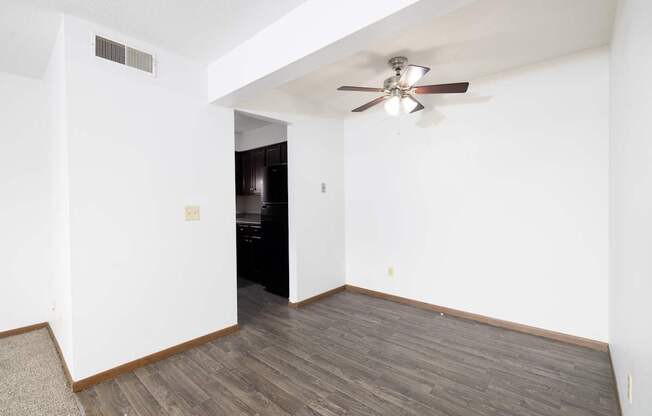 A room with a ceiling fan and wooden flooring.
