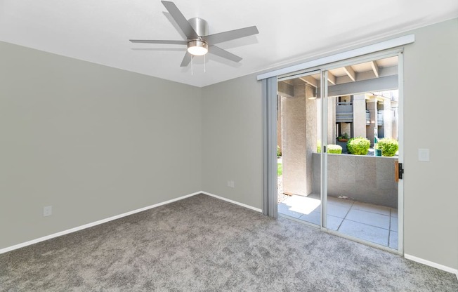 A room with a ceiling fan and carpeted floor.