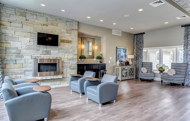 A living room with a stone fireplace and grey couches.