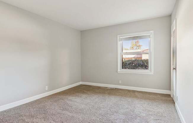 A room with a window showing a view of a building outside.