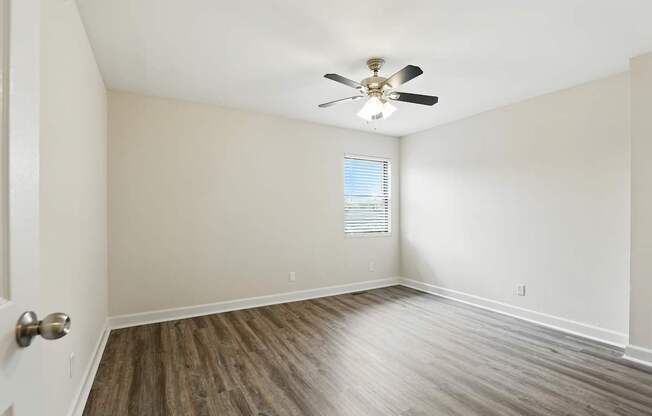 A room with a ceiling fan and wooden flooring.