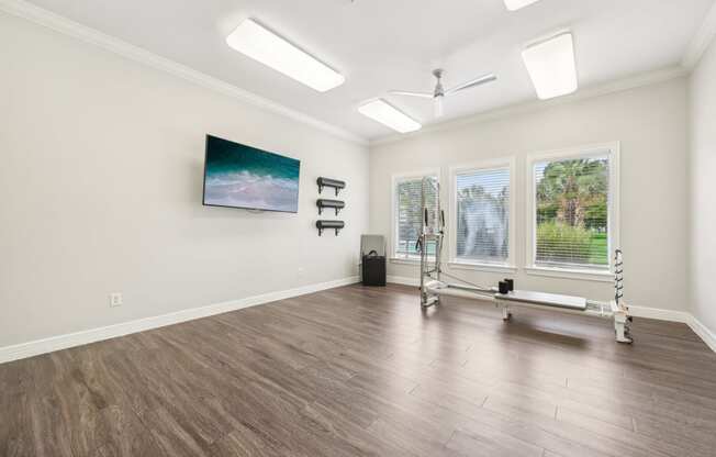 a yoga room with a reformer and three windows on the wall