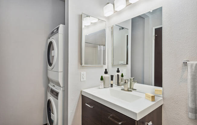 a bathroom with a sink and mirror next to a washer and dryer