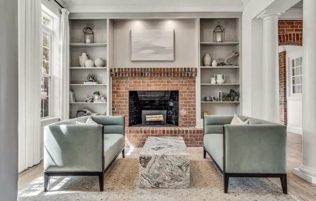a living room with two green chairs and a brick fireplace