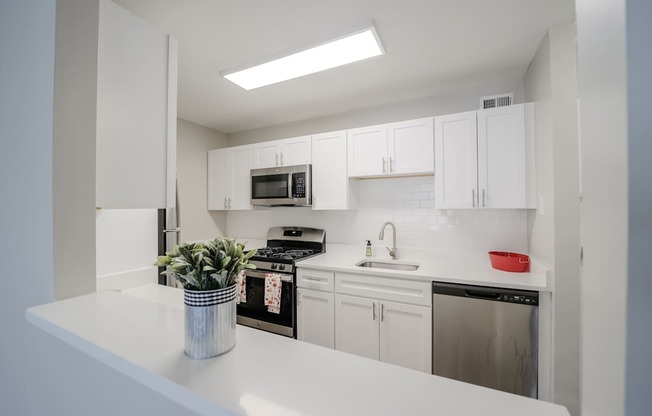 A white kitchen with a stove, oven, microwave, and cabinets.