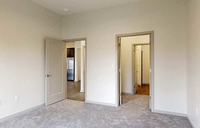 a bedroom with a walk-through closet to the attached bathroom and a door to the living room
