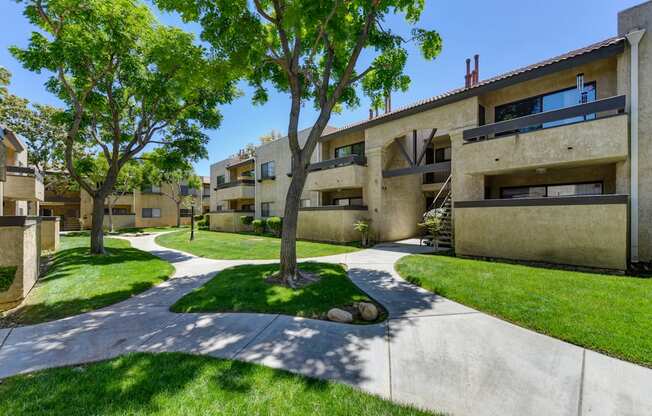 Community Walk Paths with apartment buildings on all sides and mature tress in the center.