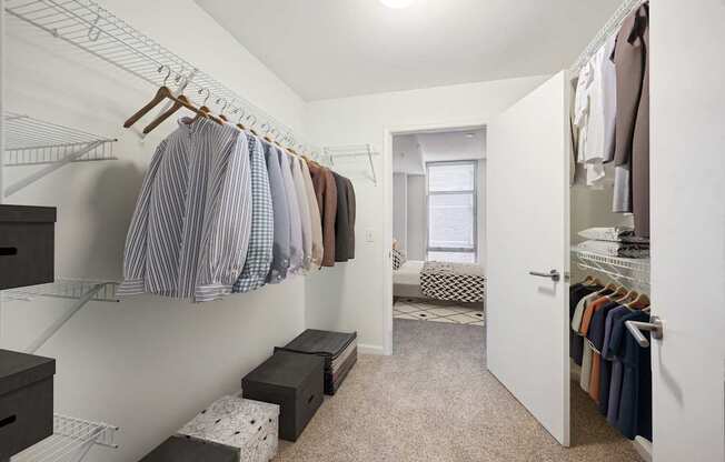 a walk in closet with clothes hanging on a rack and a door to a bedroom