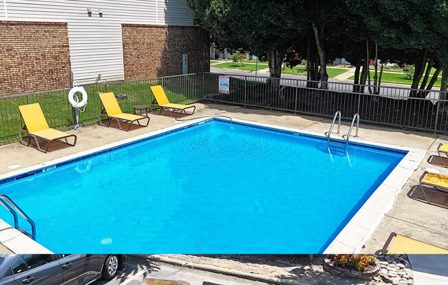 A small pool with a fence around it and a car parked in front.