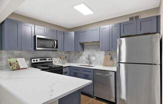 A kitchen with a white counter top and stainless steel appliances. at Mill House at East Cobb, Marietta, GA 30067