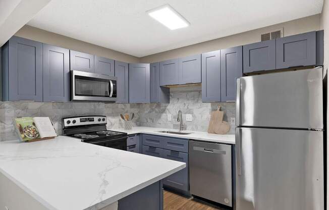 A kitchen with a white counter top and stainless steel appliances. at Mill House at East Cobb, Marietta, GA 30067