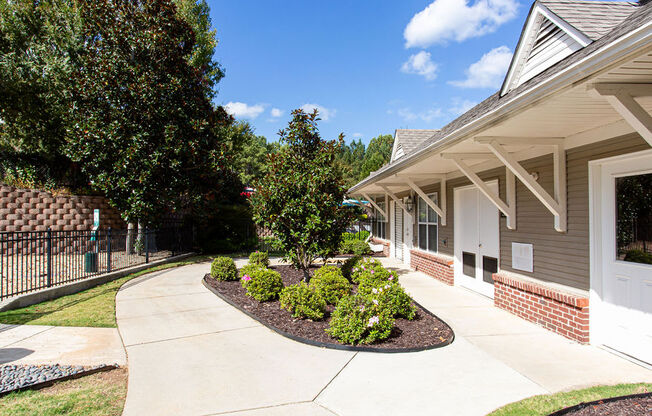 a sidewalk in front of a house with a yard and trees