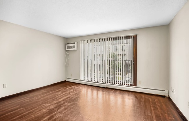 the spacious living room with wood flooring and a large window