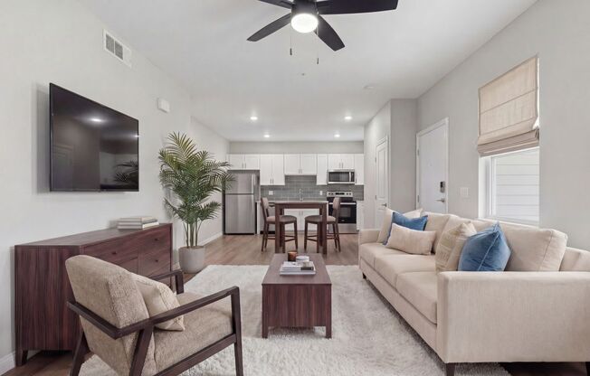 Modern open-concept living room with cozy neutral tones, stylish furniture, and sleek kitchen in the background at Summit on Boulder Apartments near Las Vegas in Henderson NV
