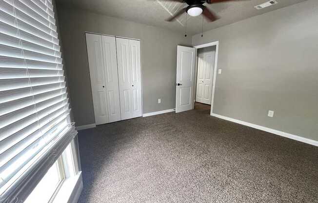 A room with a ceiling fan and carpeted floor.